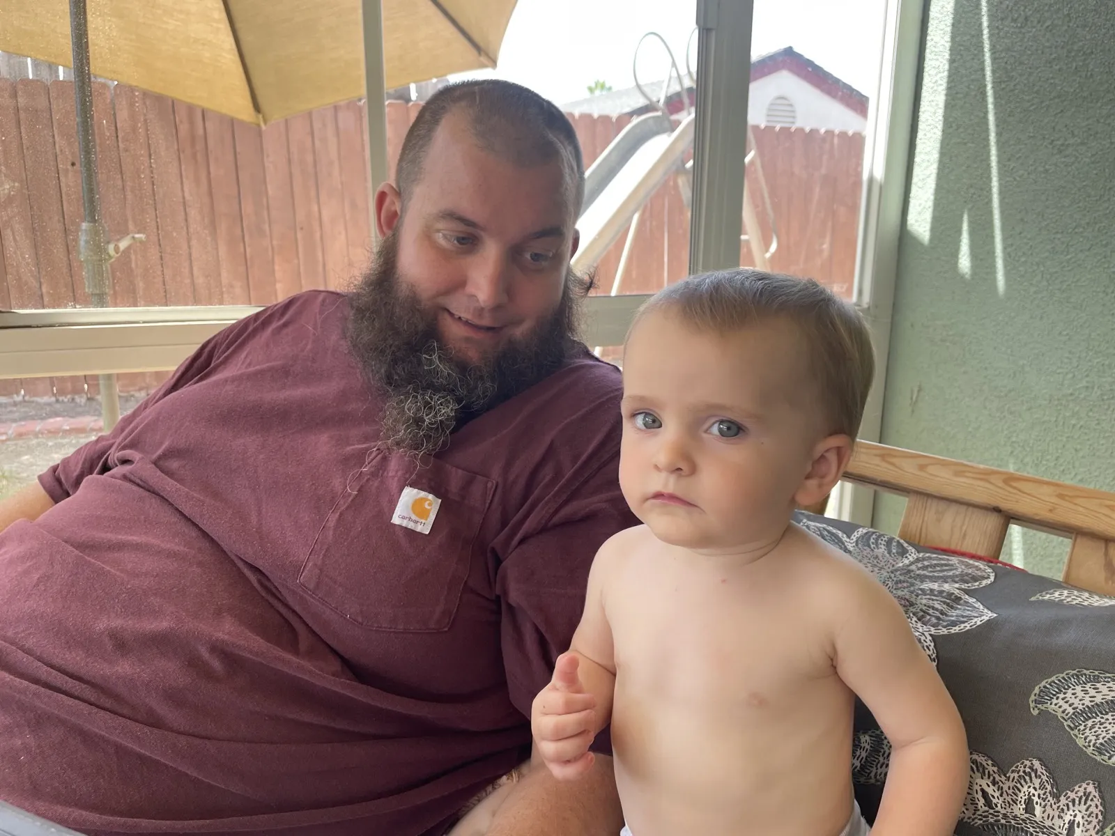 Kevin, before weight loss, sitting on a backyard porch with a baby